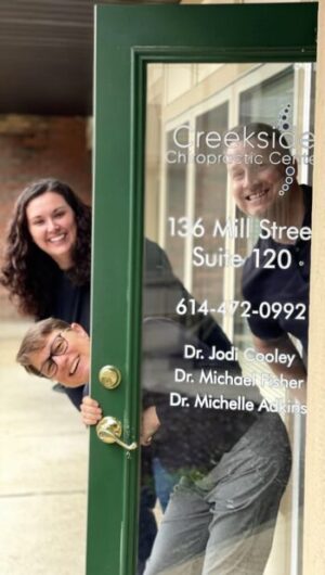 The doctors smiling while peeking around their front door.